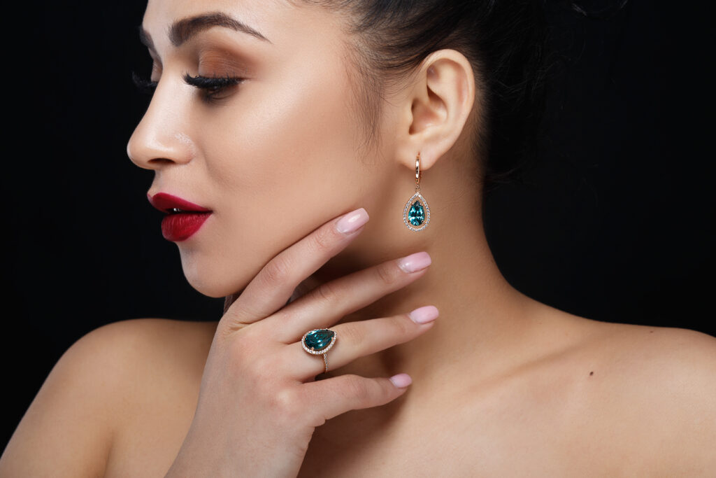 model shows earrings and ring with beautiful blue precious stone